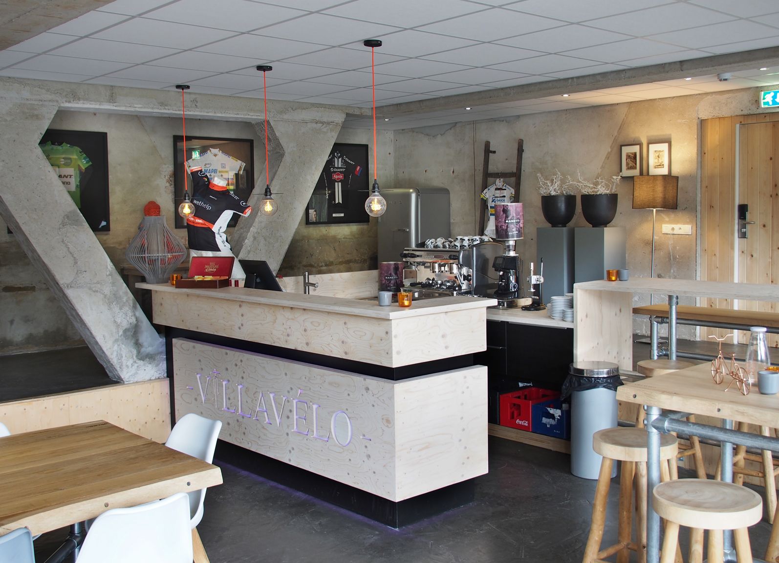 L’intérieur d’un café moderne, avec un comptoir en bois, un espace salon et une décoration de style industriel.