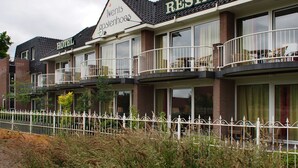 A hotel with a restaurant on the upper floor, featuring balconies with outdoor furniture. - Villavelo Twente (Ootmarsum)