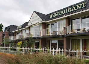 A hotel with a restaurant on the upper floor, featuring balconies with outdoor furniture. - Villavelo Twente (Ootmarsum)