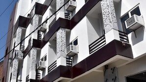 Un edificio de varios pisos con balcones, unidades de aire acondicionado y materiales de construcción.
