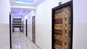 Un pasillo con piso de mármol, puertas de madera y una escalera.