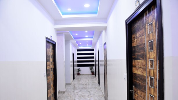 Un pasillo con puertas de madera, piso de mármol e iluminación empotrada en el techo.