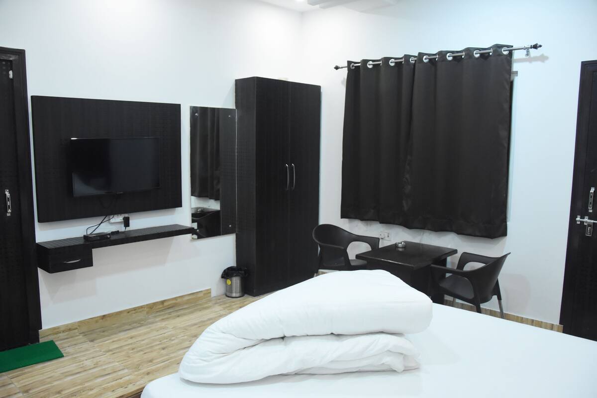 A hotel room with a bed, a desk, a chair, a TV, and a wardrobe.