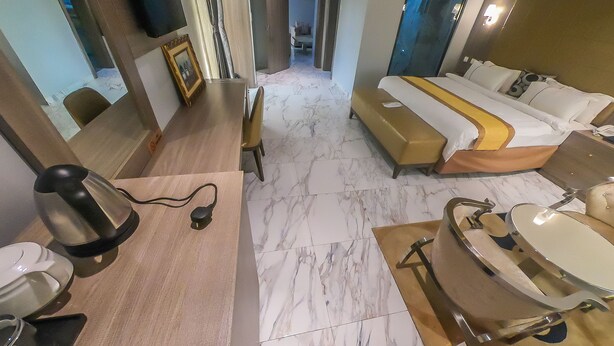 A hotel room with a bed, bedside table, and a bathroom with a sink and mirror. - Maxbe Continental Hotel (Enugu)