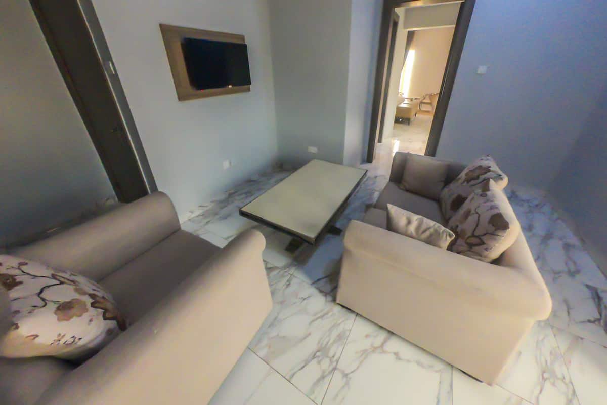 Un salon avec deux canapés, une table basse et un téléviseur à écran plat fixé au mur.