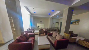 A modern living room with a sofa set, a coffee table, and a dining area in the background. - Maxbe Continental Hotel (Enugu)