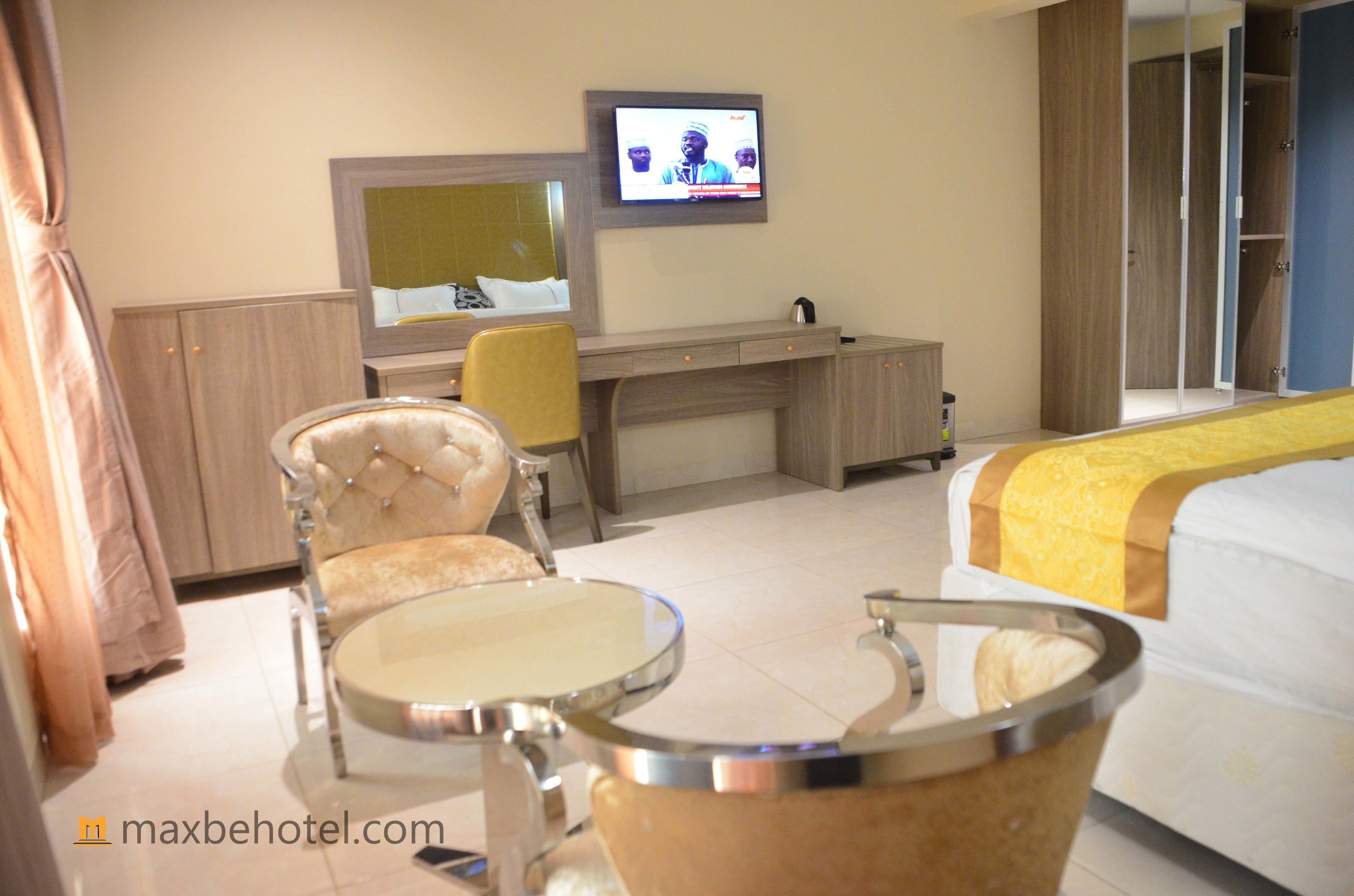 A hotel room with a bed, a desk with a chair, a television, and a wardrobe.