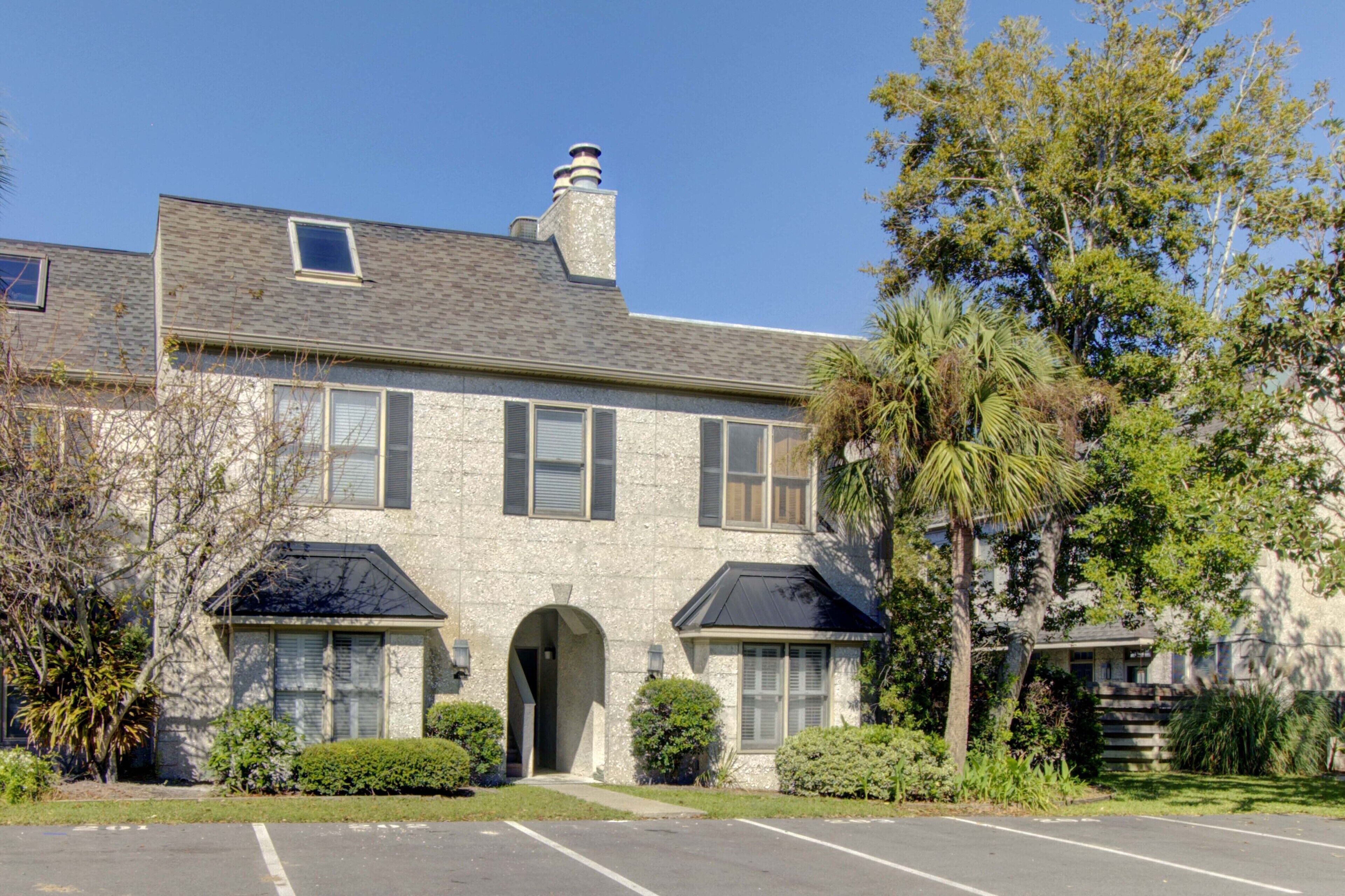 A two-story stone building with a central entrance, a covered driveway, and a parking area.