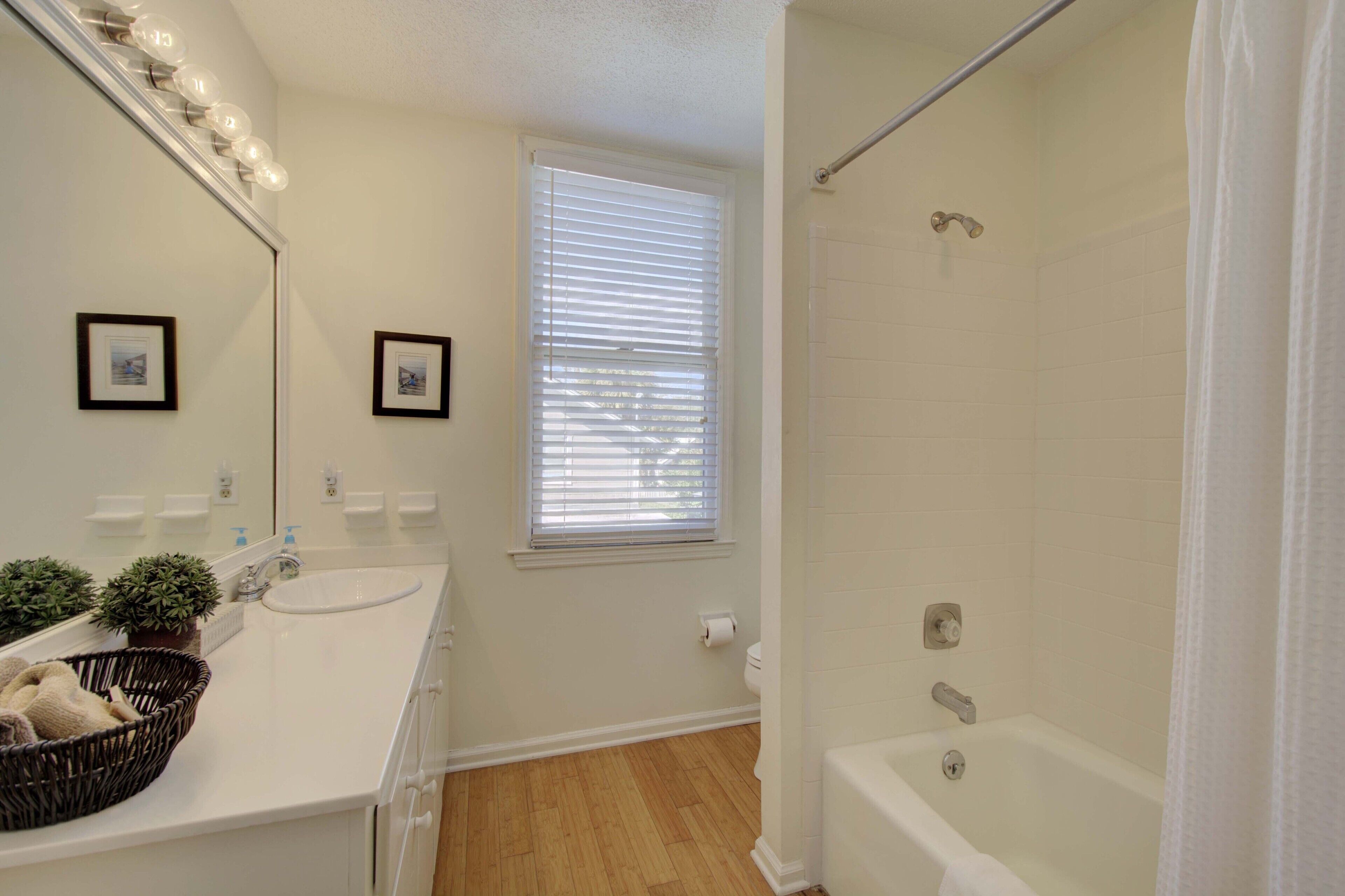 A bathroom with a white sink, mirror, and a shower with a curtain.