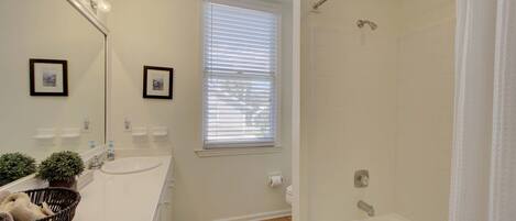 A bathroom with a white sink, mirror, and a shower with a curtain.