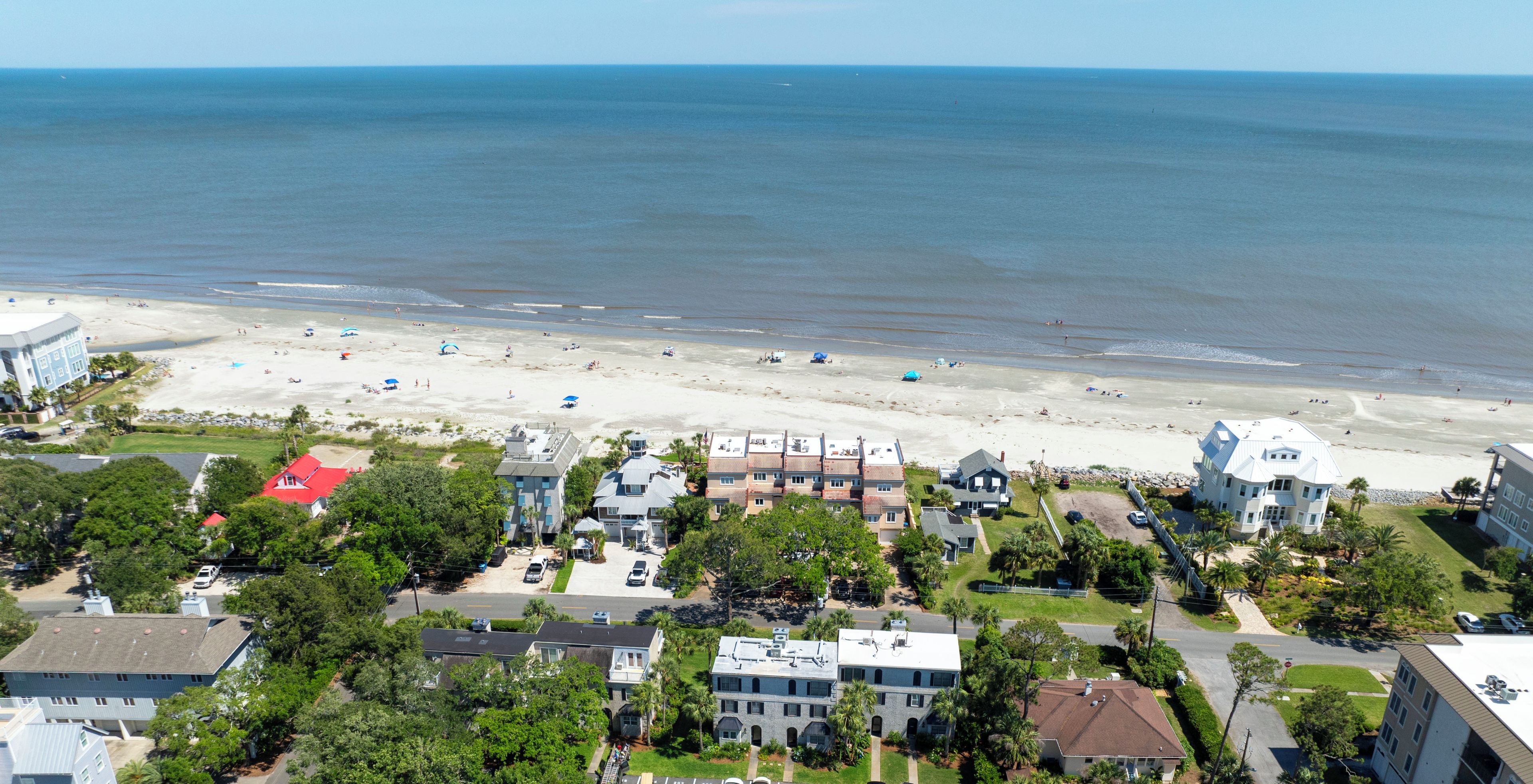 An aerial view of a coastal residential area with houses, a beach, and a clear sky.