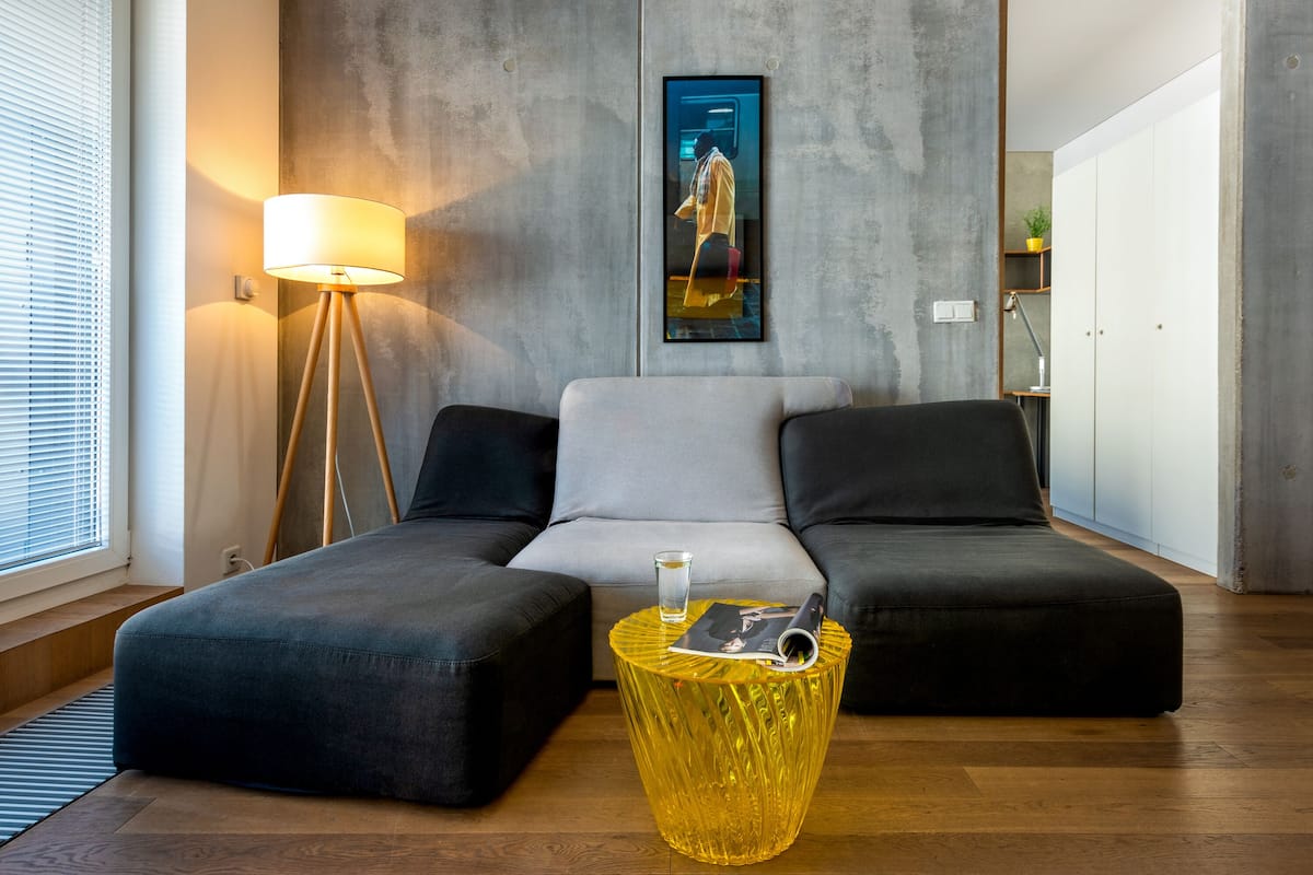 Een moderne woonkamer met een hoekbank, een glazen salontafel en een vloerlamp.