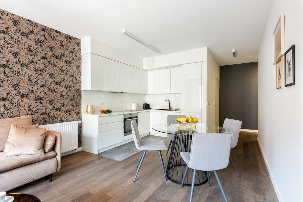 Een moderne keuken met witte kasten, een eettafel met stoelen en een zithoek met een bank.
