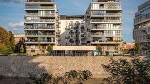 Een modern meerhoogbouwgebouw met balkons, grote ramen en een stenen muur op de voorgrond.