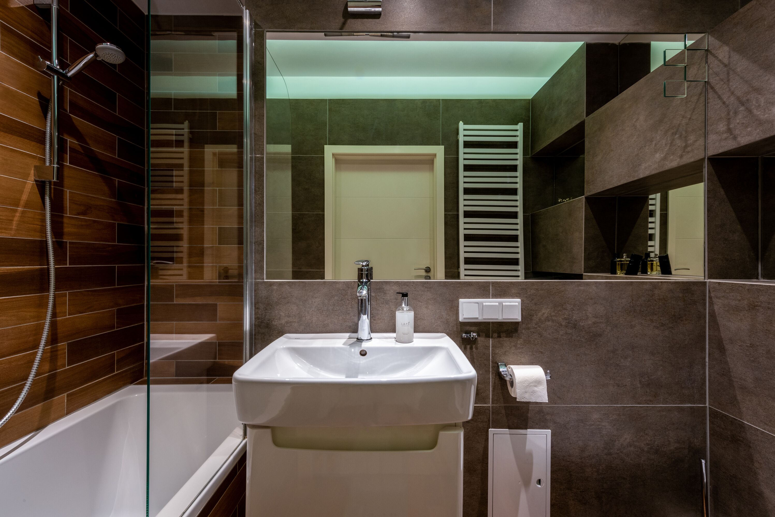 A modern bathroom with a glass-enclosed shower, a white sink, and a towel rack.