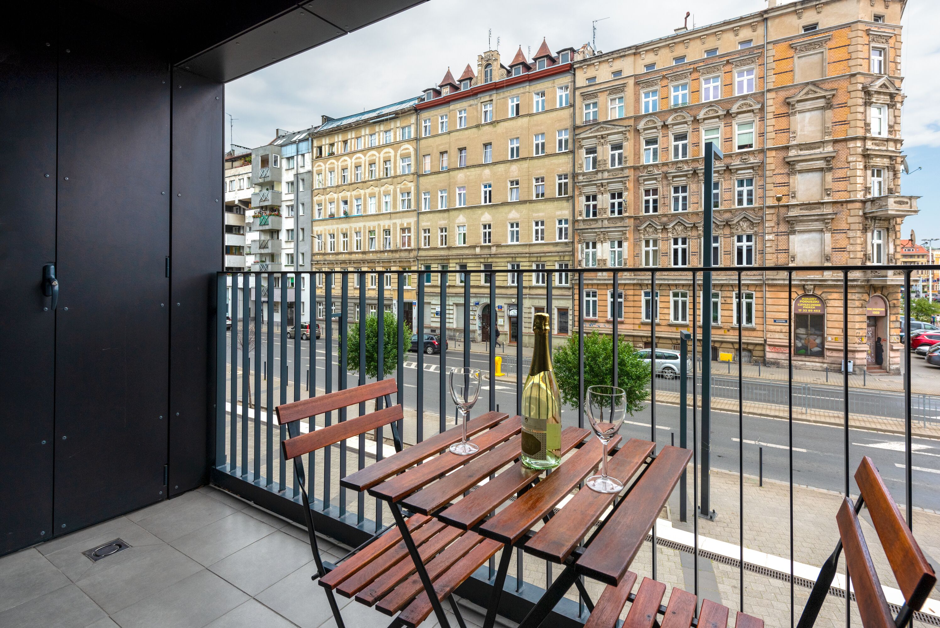 A balcony with wooden benches, a bottle of champagne, and wine glasses.