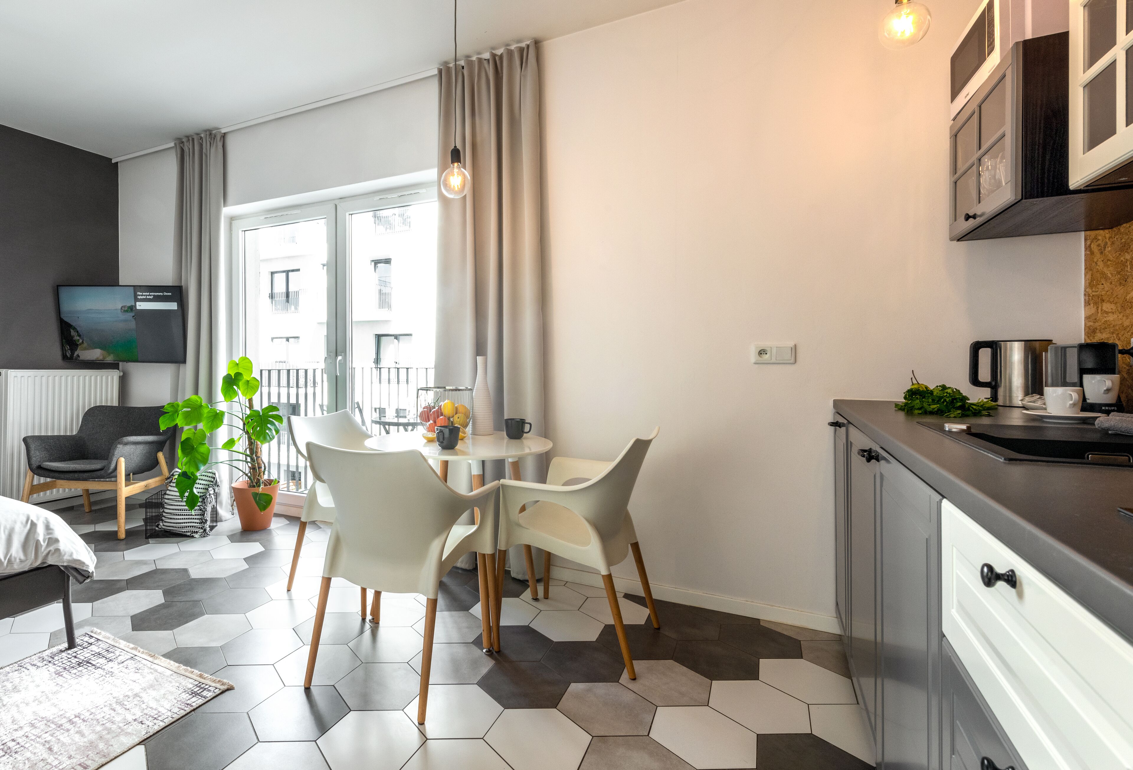 Eine moderne Küche mit Essbereich, ausgestattet mit einem großen Fenster, einem Topfpflanzen und einem Fernseher an der Wand.