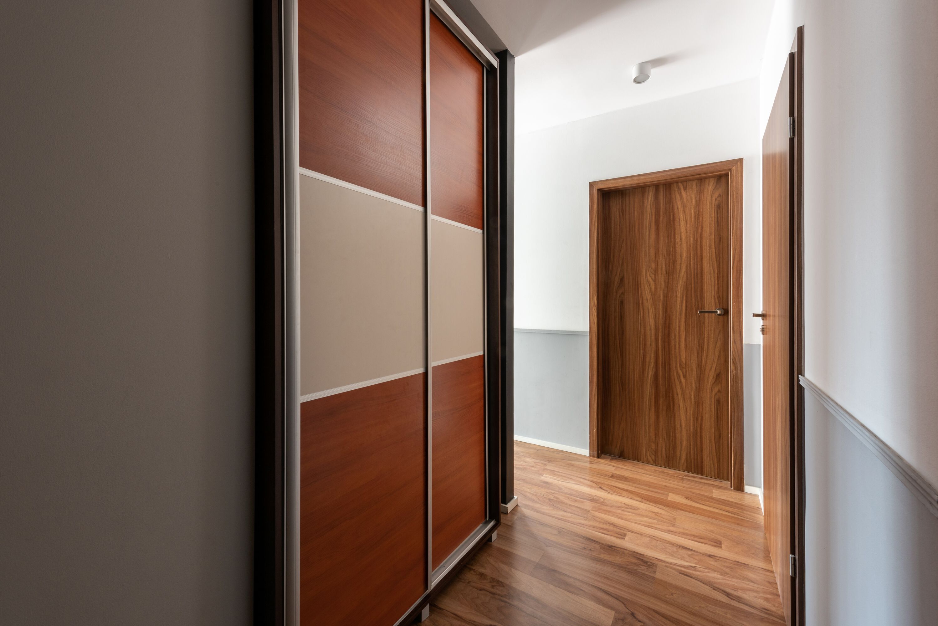 A hallway with a sliding door and a wooden door at the end.