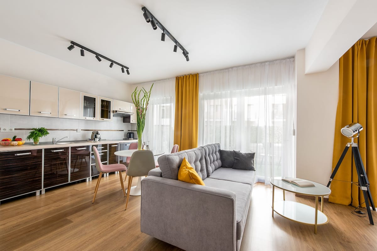 Een moderne woonkamer met een bank, een klein rond tafeltje en een driepootlamp.