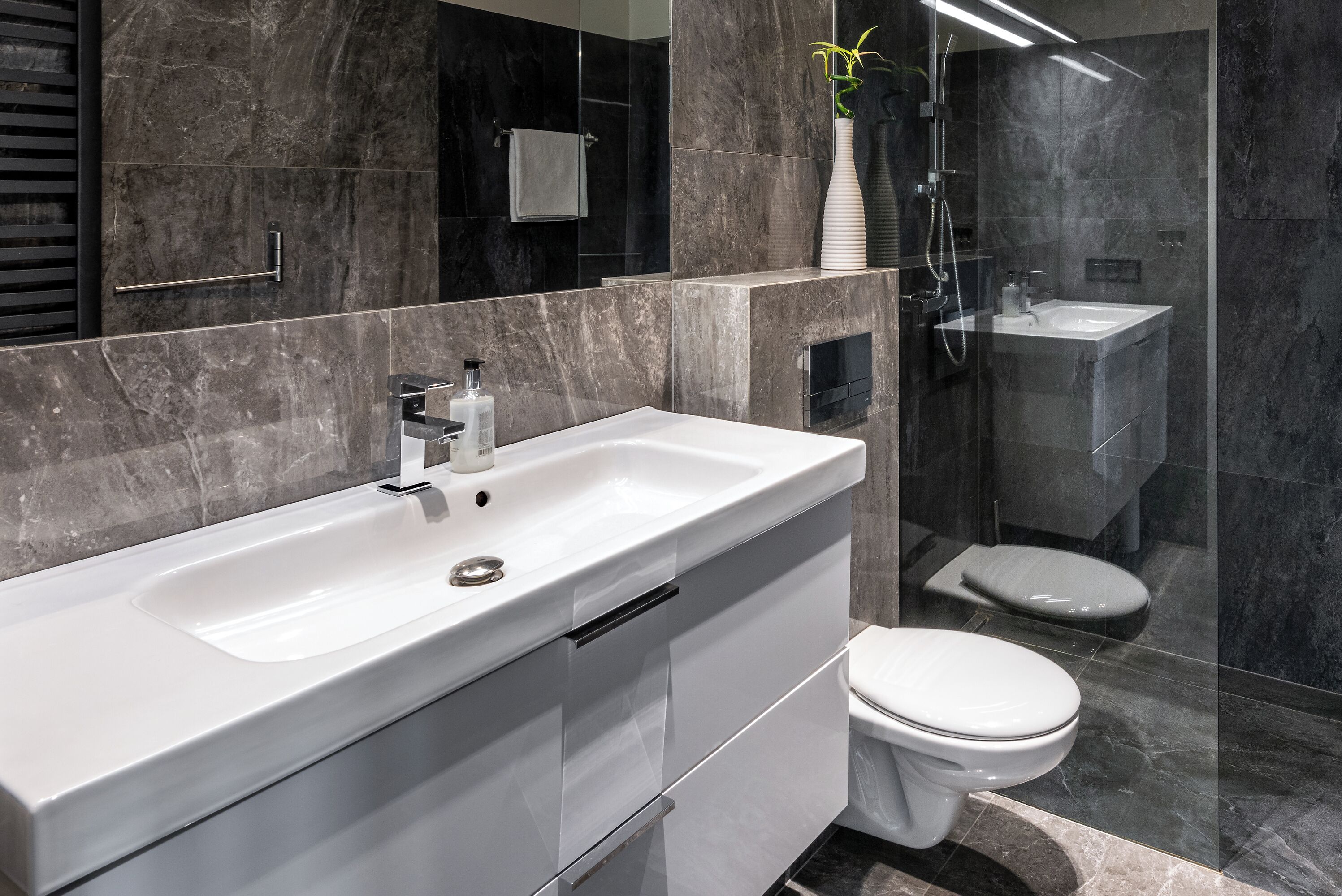 Ein modernes Badezimmer mit Waschbecken, Toilette und einer Duschkabine.
