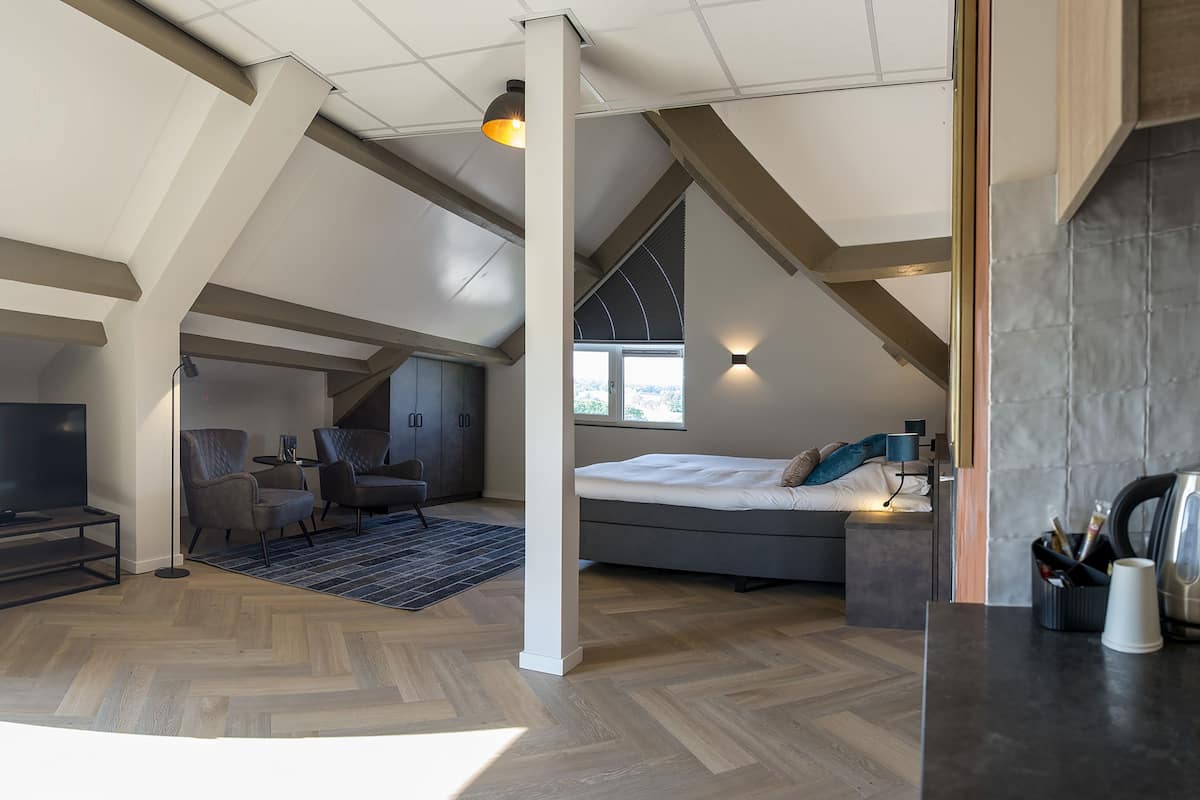 A spacious loft bedroom with a large bed, a desk, and a TV in a separate area.