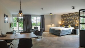 A modern hotel room with a large bed, a dining area, and a view of the outdoors. - Heuvelrijk Berg en Dal (Groesbeek)