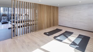 A modern gym with exercise equipment, wooden partitions, and black exercise mats.