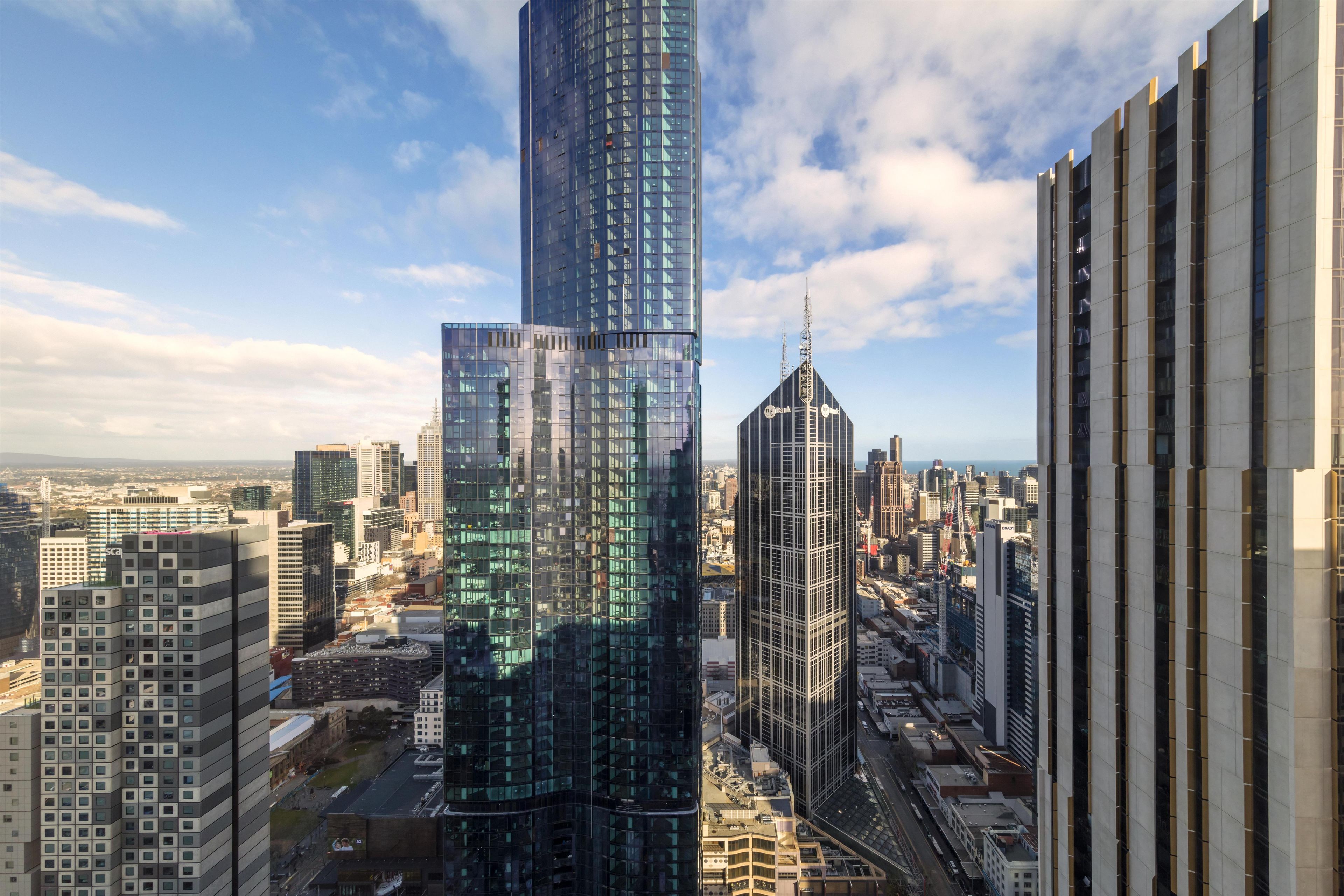 A high-rise building with a modern glass facade, surrounded by other tall buildings in an urban setting.