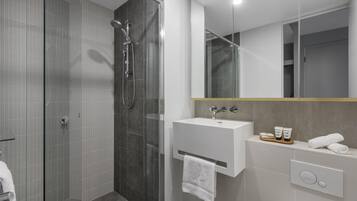 A modern bathroom with a glass-enclosed shower, a white sink, and a mirror with a gold frame.