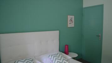 Una habitación con una cama, una mesa redonda pequeña, una puerta y un cuadro en la pared.
