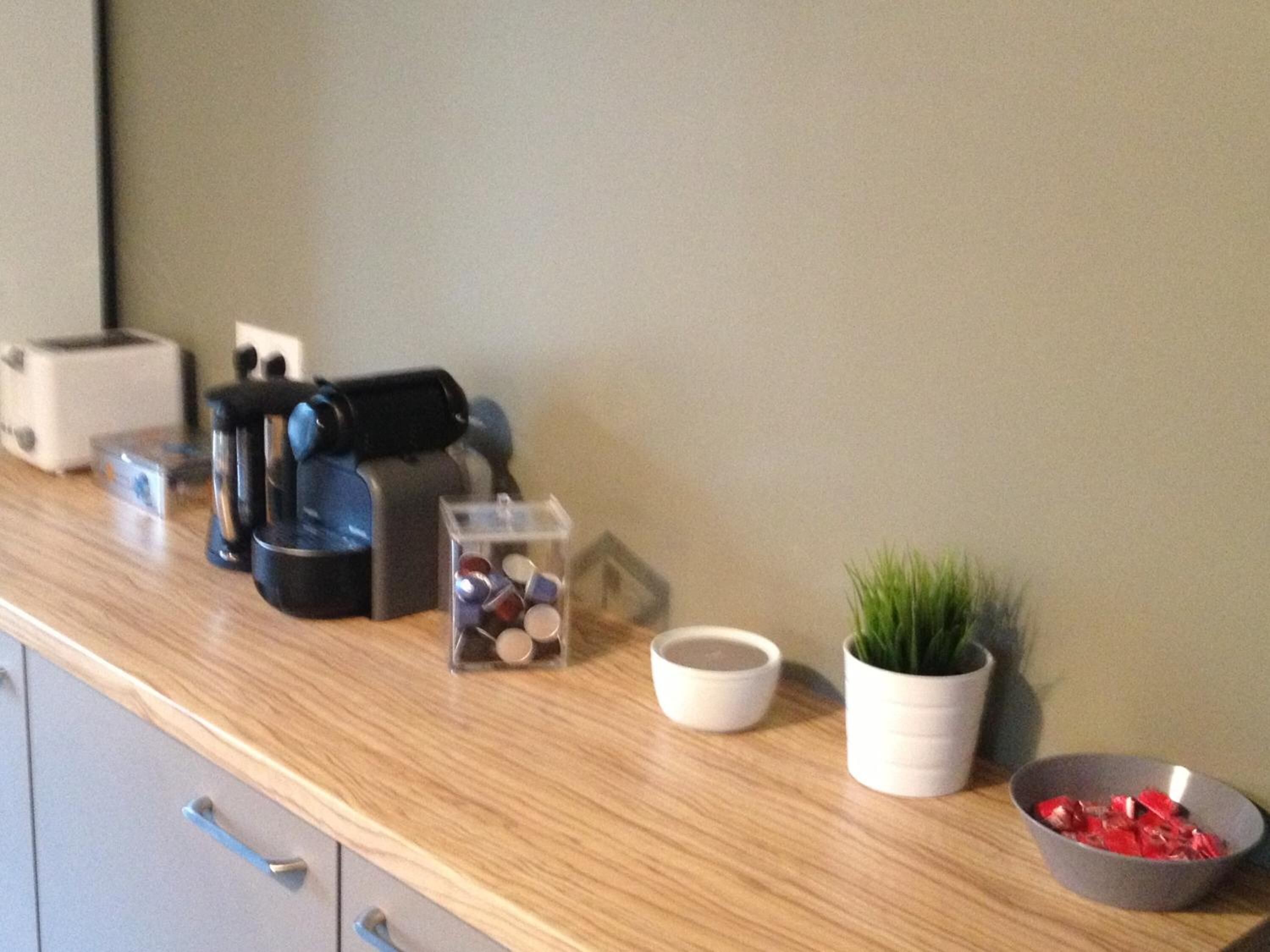 A kitchen counter with a toaster, coffee maker, and a small potted plant.