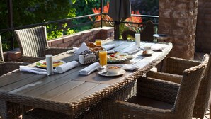 A wicker dining table with breakfast items, a glass of orange juice, and a cup of coffee. - Premium Village Residence (Hora)
