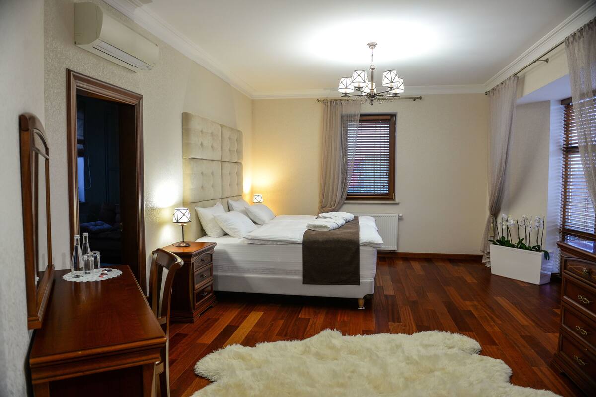 Un dormitorio con cama, mesitas de noche, cómoda, espejo y candelabro.