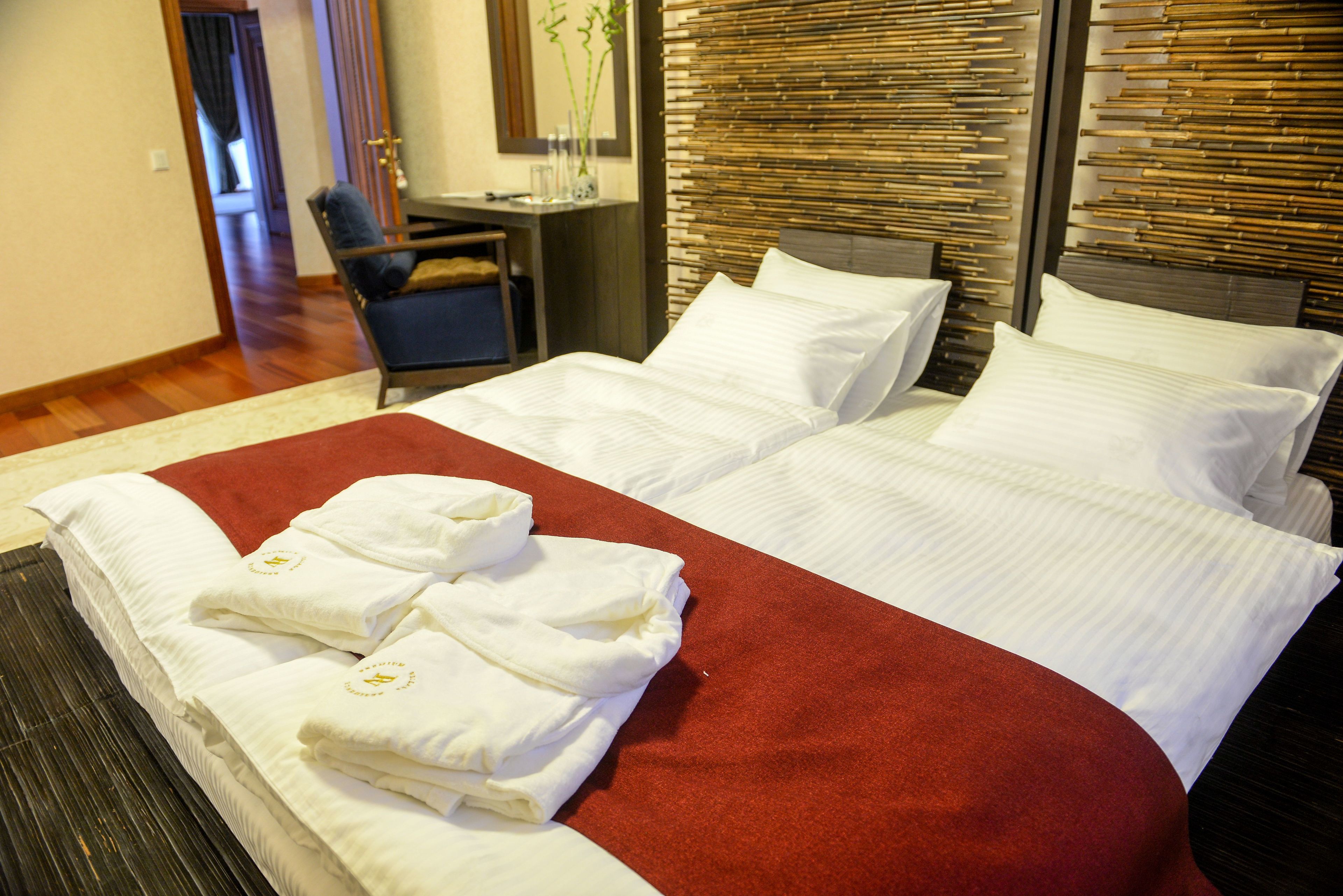 A hotel room with a large bed, a desk with a chair, and a mirror on the wall.