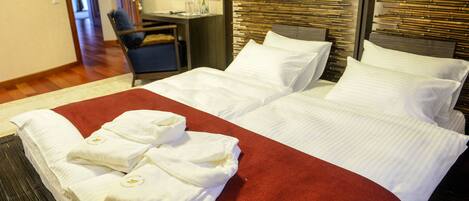 A hotel room with a large bed, a desk with a chair, and a mirror on the wall.