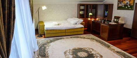 A hotel room with a bed, a desk, a lamp, a chair, and a painting on the wall.