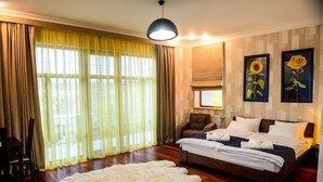 A bedroom with a large bed, a chair, a sofa, a fluffy rug, and two framed pictures on the wall. - Premium Village Residence (Hora)