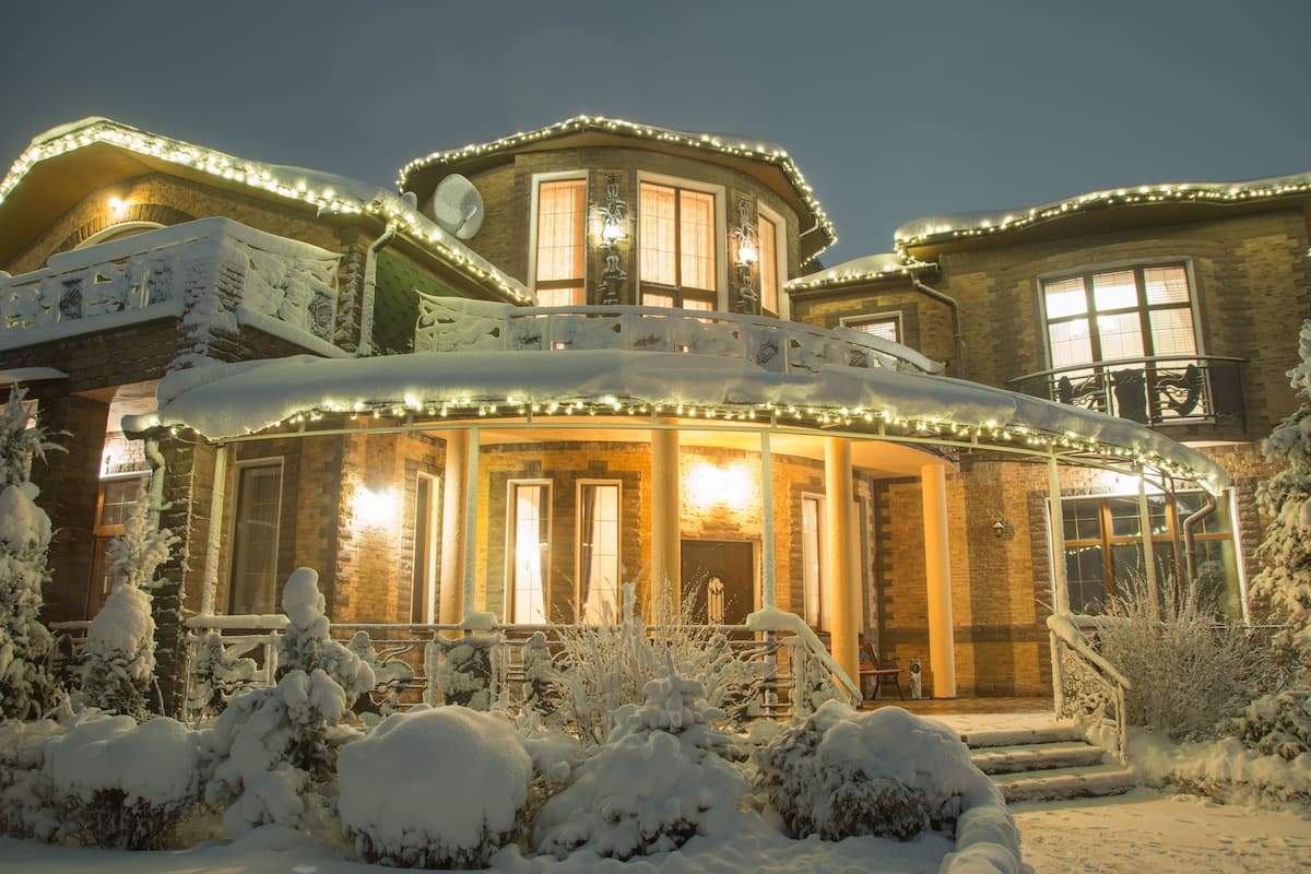 Una casa cubierta de nieve con una entrada cálida y acogedora y un porche bien iluminado.