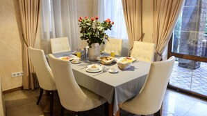 A dining area with a table set for breakfast, including plates, cups, and a vase of flowers. - Premium Village Residence (Hora)