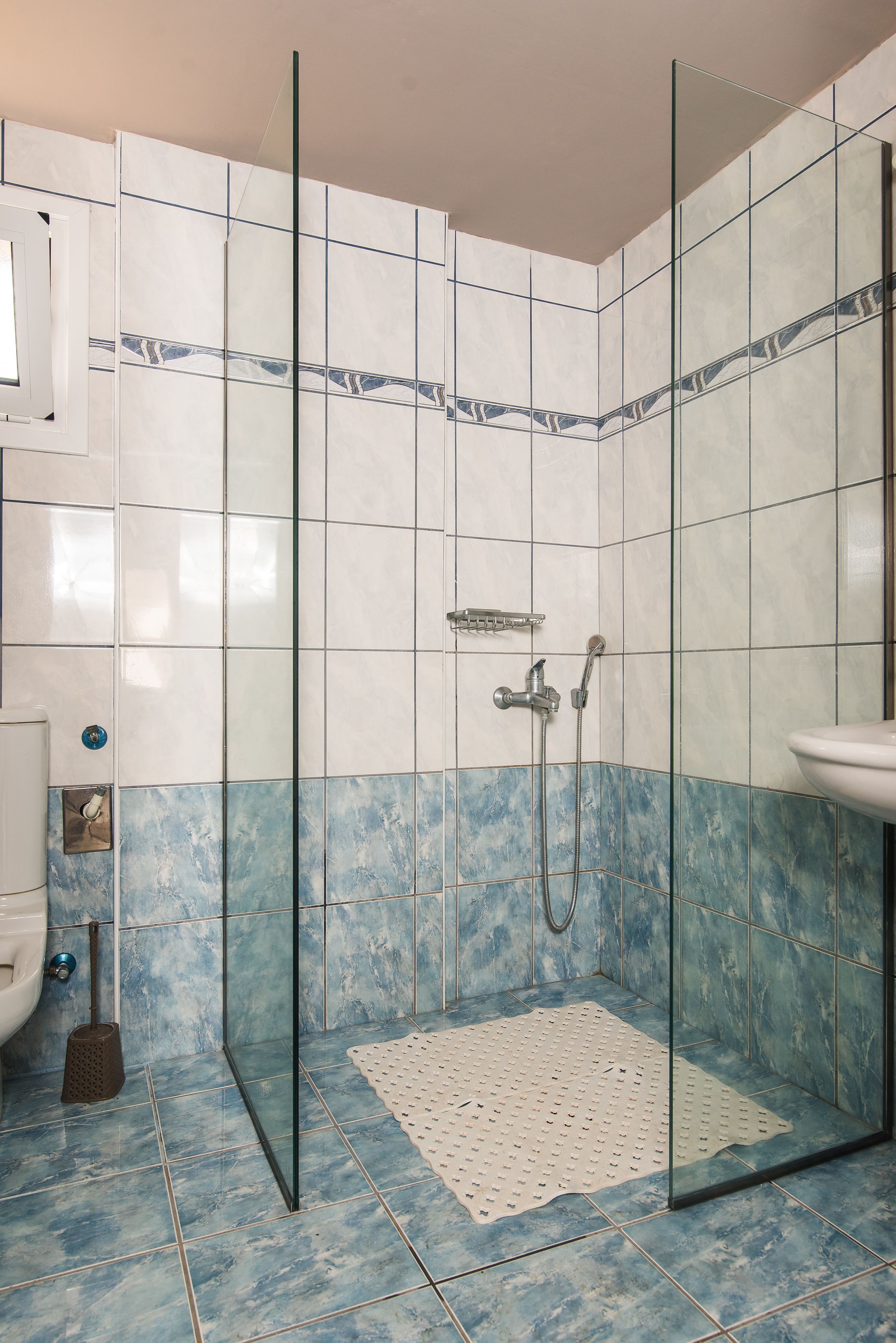 A shower area with glass doors, a tiled floor, and a showerhead.