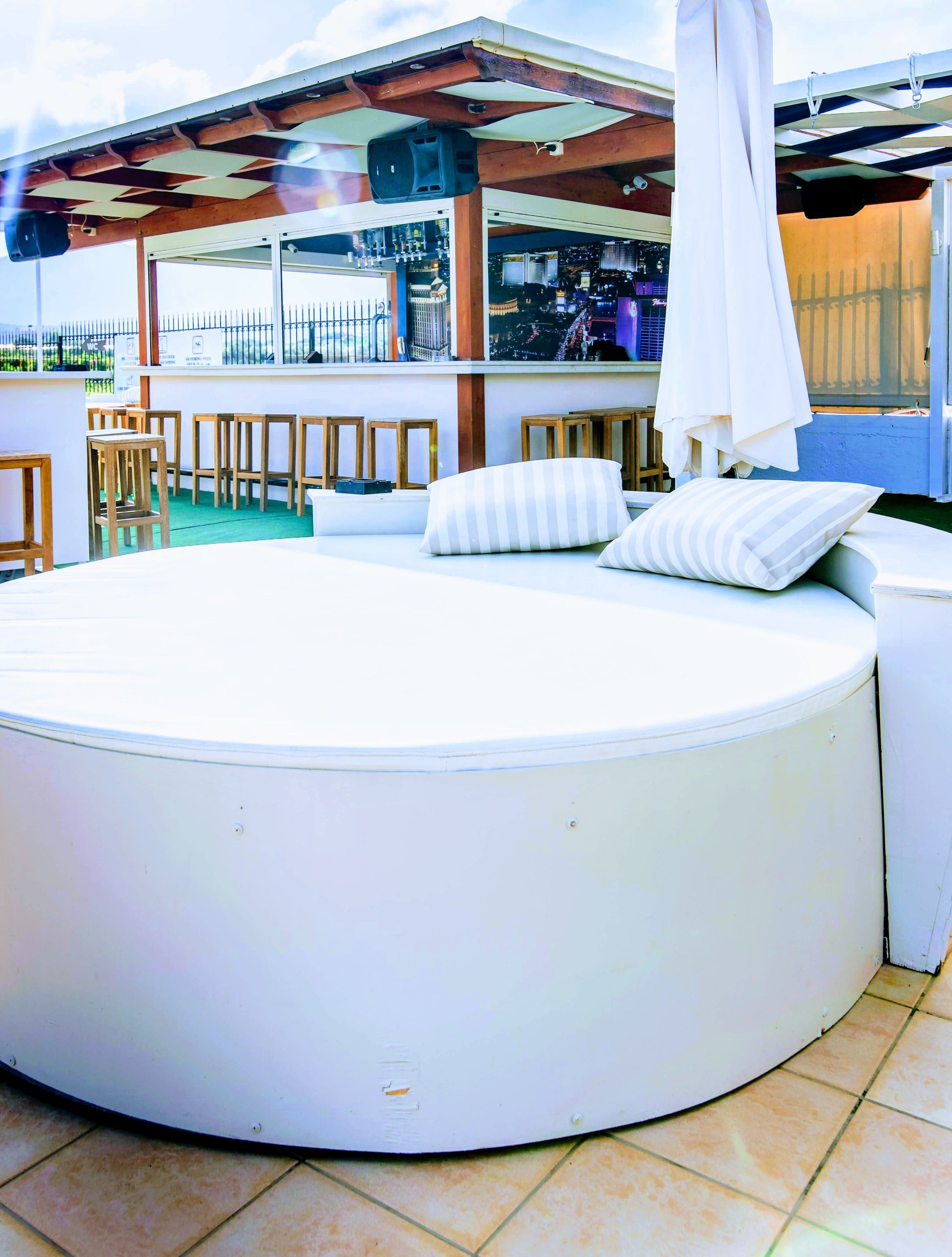A round, white outdoor seating area with cushions and a white umbrella.