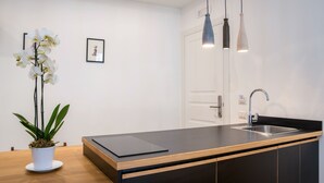 A modern kitchen with a black countertop, wooden cabinets, a stainless steel sink, and pendant lighting. - Napoliamo Guest House (Naples)