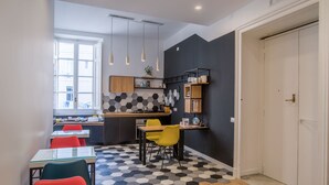 A modern kitchen with a hexagonal tile floor, a dining area with colorful chairs, and a black accent wall. - Napoliamo Guest House (Naples)