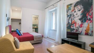 Een moderne hotelkamer met een bed, een bank, een televisie en een groot abstract schilderij.
