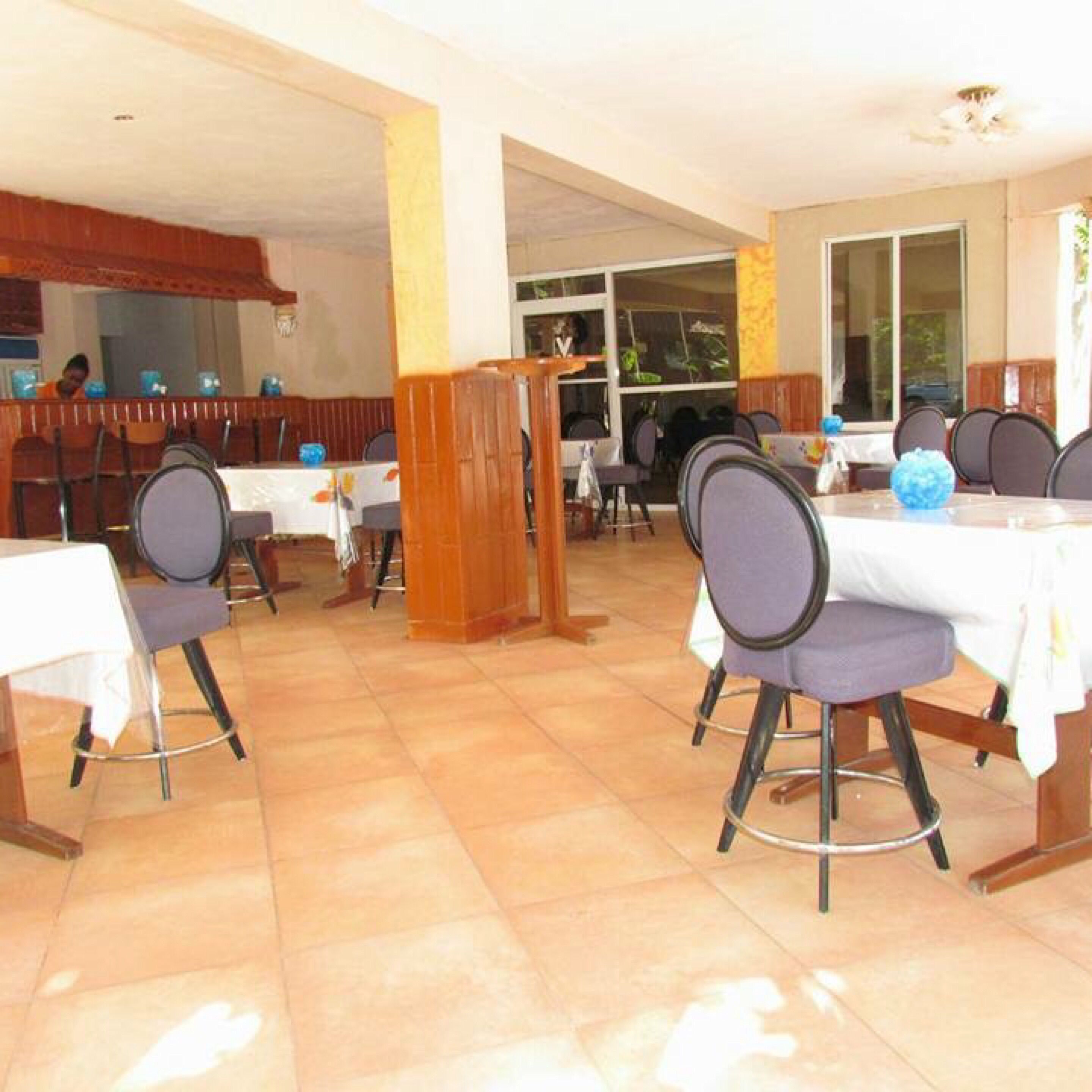 A restaurant with tables and chairs, a wooden counter, and a view of the outdoors.