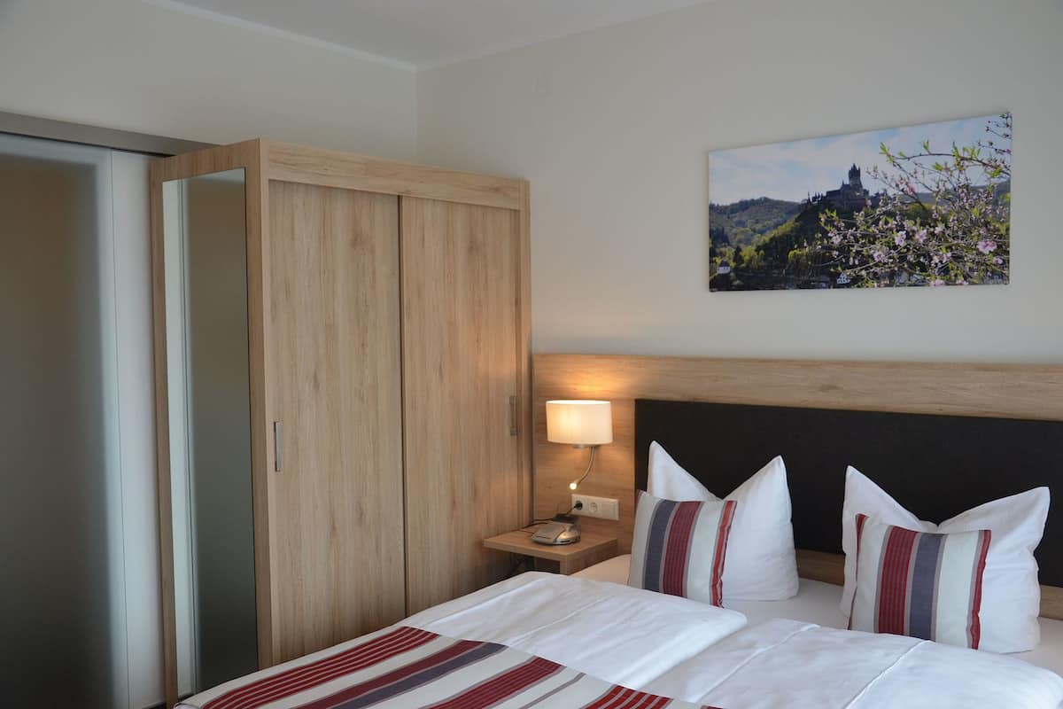 Quarto de hotel com cama, mesa de cabeceira, abajur, guarda-roupa e um quadro na parede.
