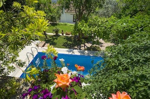 Una piscina al aire libre, sombrillas, sillones reclinables de piscina
