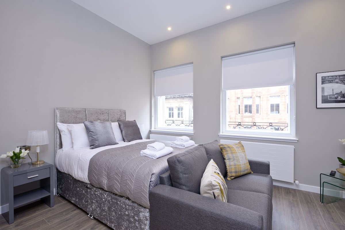 Une chambre à coucher moderne avec un lit, une table de chevet et un canapé.