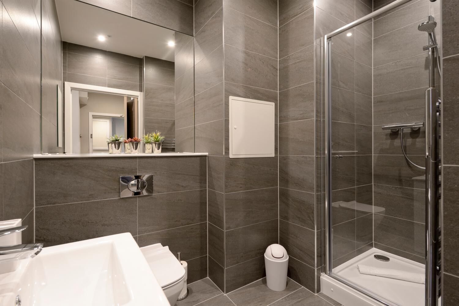 A modern bathroom with a shower, toilet, and sink.
