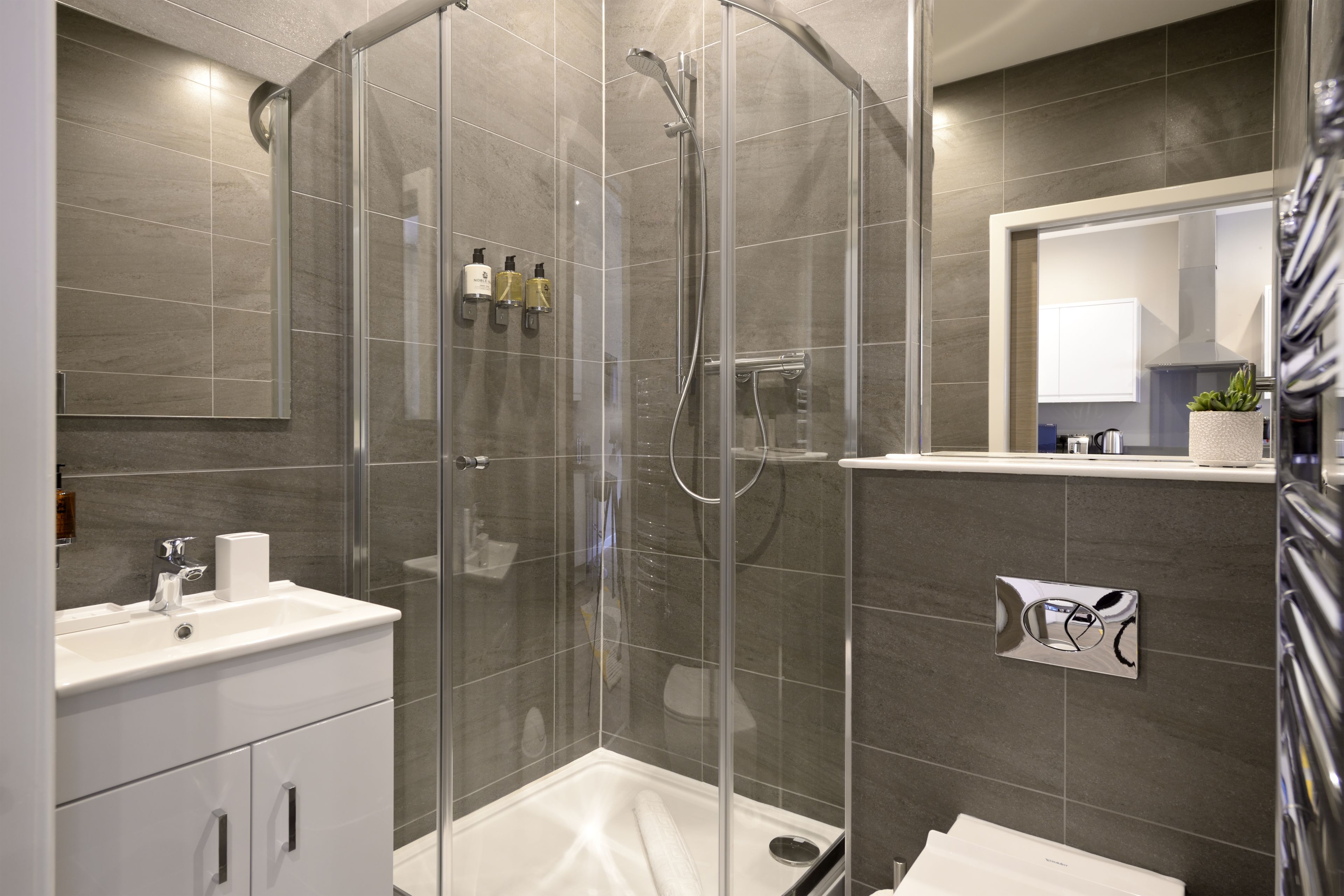 A modern bathroom with a glass-enclosed shower, a white sink, and a mirror above the sink.